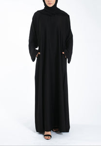 Woman wearing a black abaya and hijab on a white background