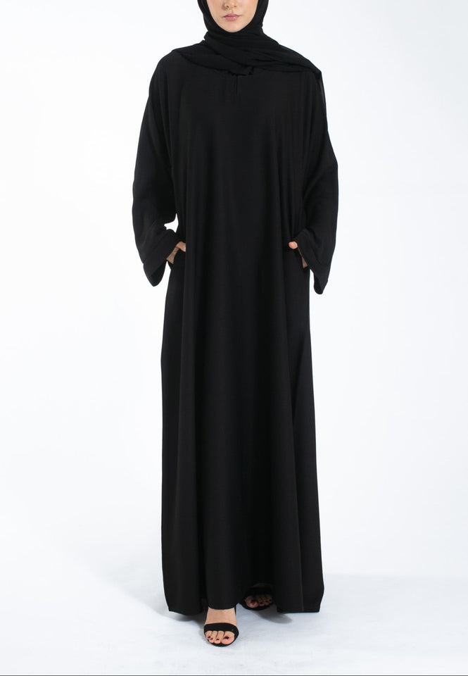 Woman wearing a black abaya and hijab on a white background