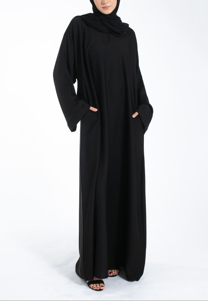 Woman wearing a black abaya and hijab on a white background