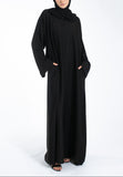 Woman wearing a black abaya and hijab on a white background