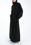 Person wearing a black abaya and hijab on a white background