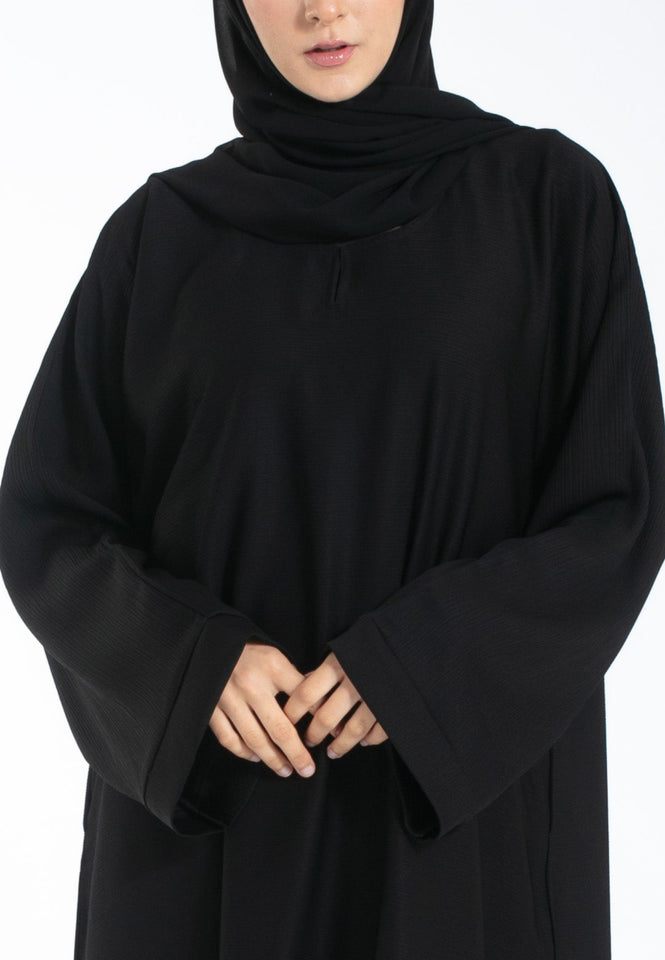 Person wearing a black abaya on a white background