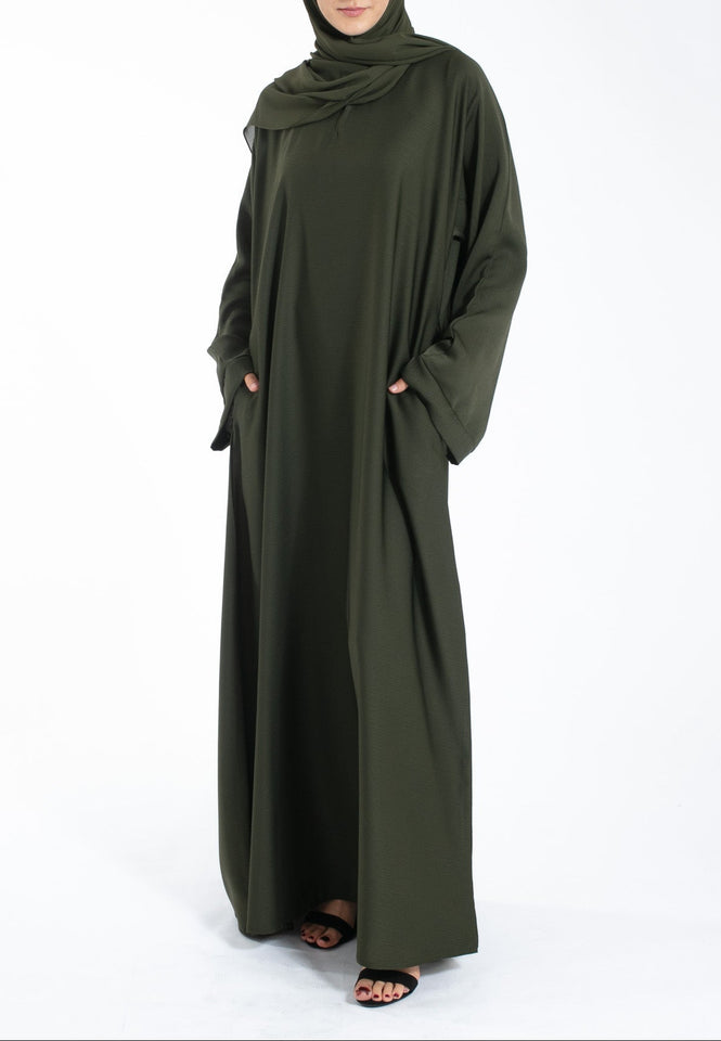 Woman wearing an olive green abaya on a white background