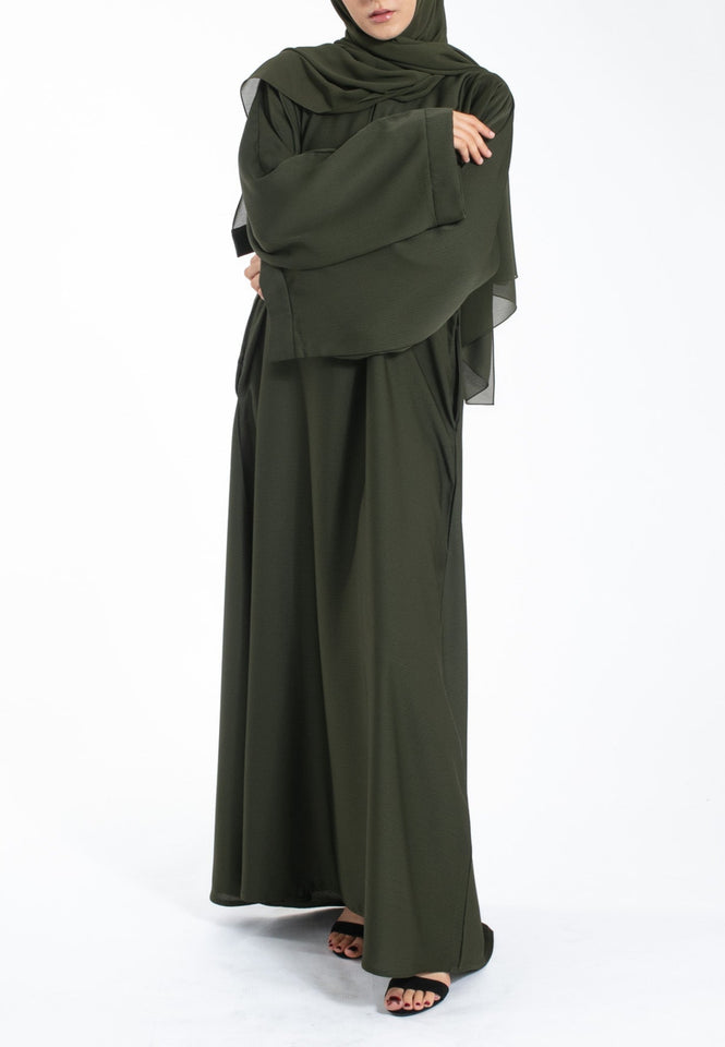 Woman wearing an olive green abaya and hijab on a white background