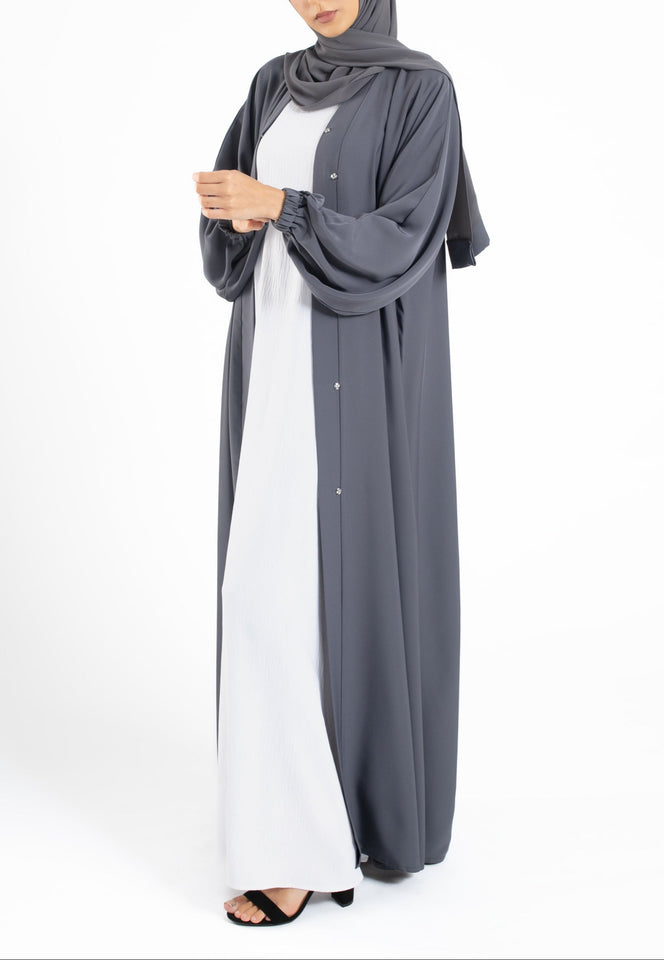 Woman wearing a long gray cardigan over a white dress on a white background