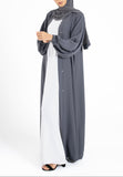 Woman wearing a long gray cardigan over a white dress on a white background