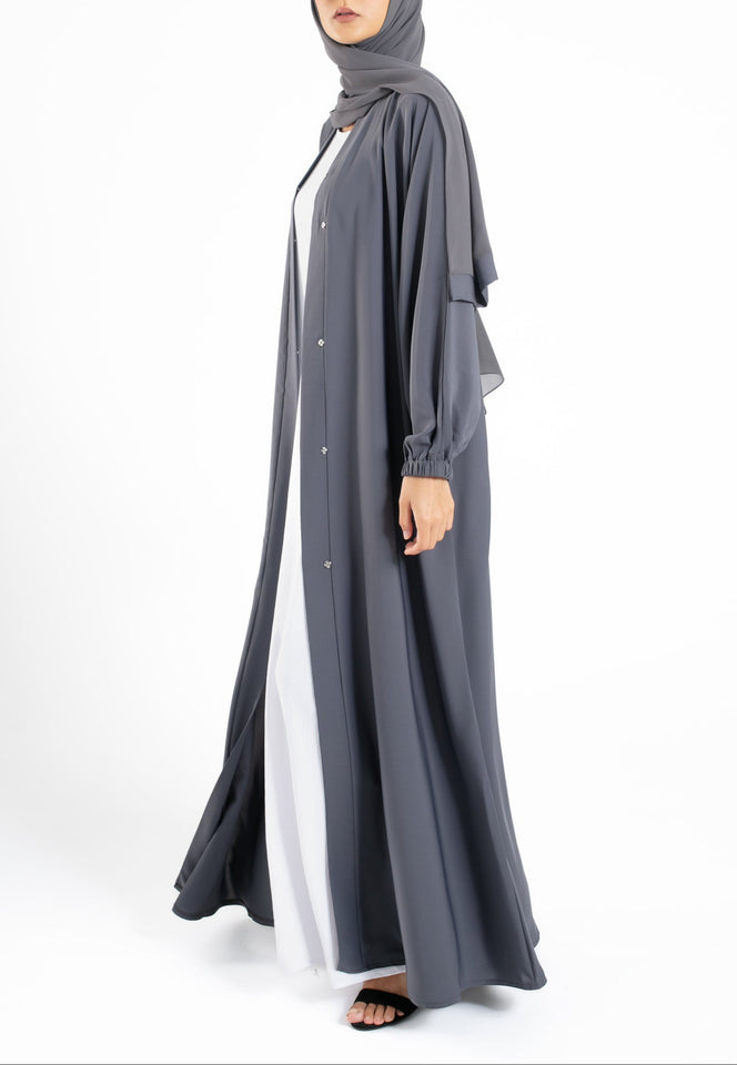 Woman wearing a long gray dress with a white shirt underneath on a white background