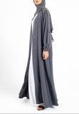 Woman wearing a long gray dress with a white shirt underneath on a white background