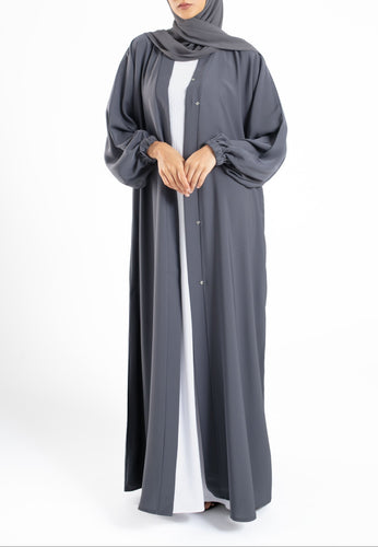 Woman wearing a gray abaya with a white shirt underneath on a white background