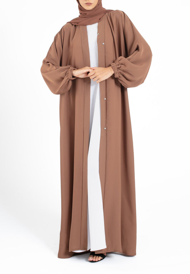 Woman wearing a brown abaya on a white background