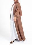 Woman wearing a brown hijab and abaya on a white background